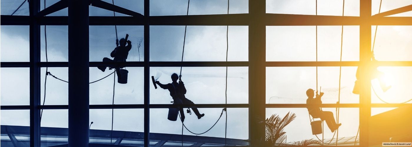 Building cleaners clean large window fronts in an airport hall and work in the field of facility management.