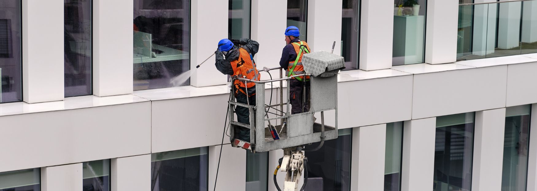 Building cleaners clean window fronts from the outside of a building. 