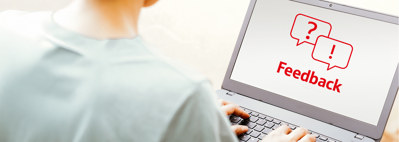 Eine Person sitzt mit dem R&uuml;cken zum Betrachter an einem Laptop. Auf dem Bildschirm ist ein Piktogramm in roter Farbe mit dem Text Feedback zu sehen.